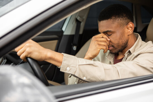 Young man sitting inside his car and feeling stressed and upset