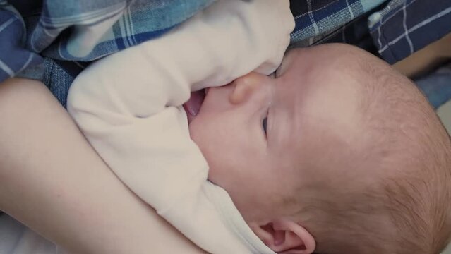 woman rocking cute sleepy baby at daytime. one month infant napping in his mother arms. vertical