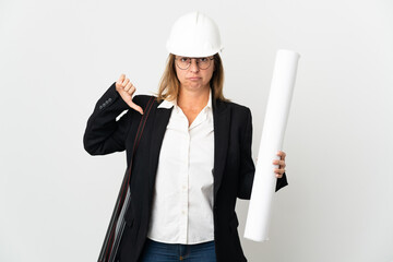 Middle age architect woman with helmet and holding blueprints over isolated background showing...
