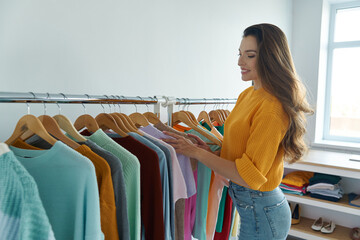 Happy young woman choosing clothes in fashion store