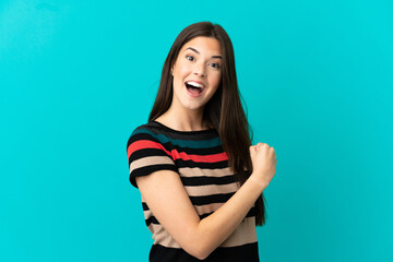 Obraz premium Teenager Brazilian girl over isolated blue background celebrating a victory