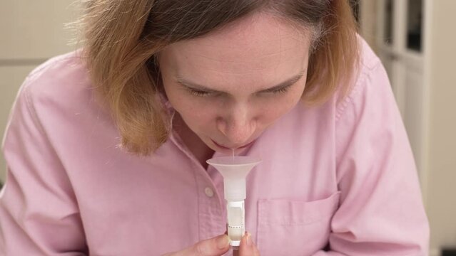 a woman collects saliva in a container for a dna test. 
