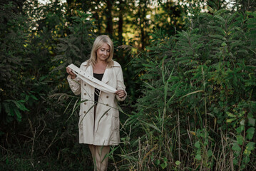 Naklejka premium A beautiful adult woman with blond hair and a light raincoat smiles