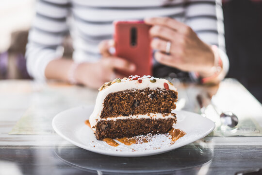 close up of a carrot cake while an unrecognizable person takes a picture of it
