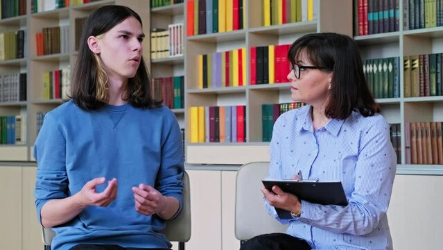 Individual therapy, social worker psychologist working with college student guy in library office