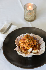 Clams in a clam shell bowl with crispy asian noodles on rice