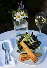 A mussels dish with wine in outdoor setting
