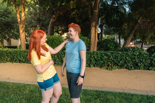 side image of two friends laughing intensely, in a city public park at sunset. young girls enjoying the summer outdoors. concept of friendship and companionship.