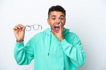 Young Brazilian man with glasses isolated on white background shouting with mouth wide open