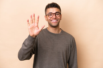Young Brazilian man isolated on beige background counting five with fingers