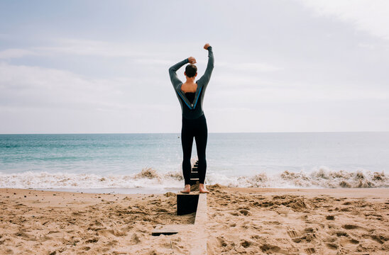 Man Zipping Up His Wetsuit At The Beach Ready To Swim In The Sea