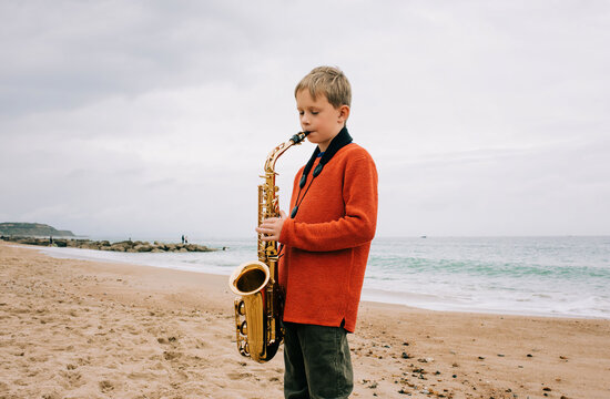boy happily playing the saxophone on a beach