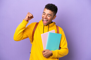 Young student Brazilian man isolated on purple background celebrating a victory