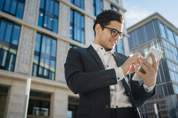 An entrepreneur with glasses uses a tablet responds to a client's letter goes to the office