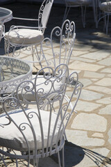 Fototapeta na wymiar Vintage retro metal outdoor white chairs on stone tiles floor.