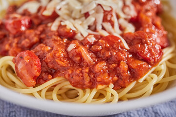 Philapine style sphaghetti with hot dog slices and banana sauce with shredded parmesan cheese