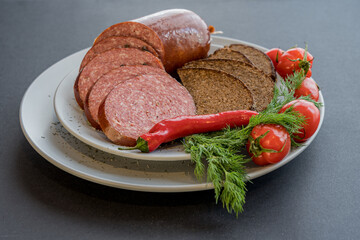 Sliced sausage, bread and vegetables with spices on plate