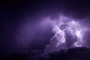 Dramatic purple storm clouds illuminated by lightning at night
