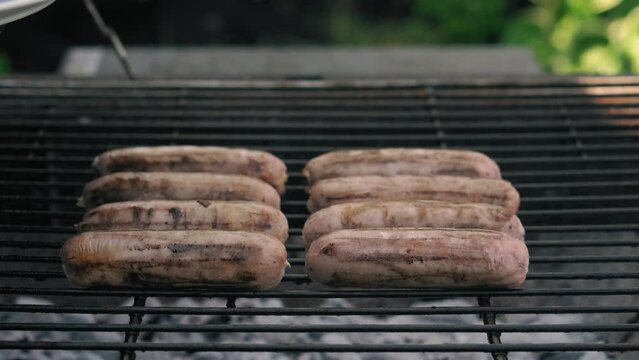 Spicy Sausages Being Grilled Over Bright Glowing Coals Broasting On Fire. Lunch Celebration Party Barbecue. Outdoor Cooking. Cook Prepares Oriental Dish In Kitchen. Junk Food, Healthy Lifestyle.
