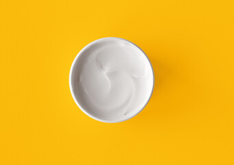 White cream jar on yellow background close-up. Beauty cosmetics presentation. Moisturizing skincare product. Top view. Trendy healthcare concept. Copy space for design. Flat lay style