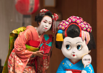 kyoto, japan - march 26 2020: Japanese female posing in a Maiko's outfit aside a character...