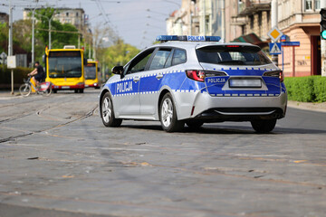 Radiowóz polskiej policji w mieście podczas patrolu na sygnale alarmowym.  - obrazy, fototapety, plakaty