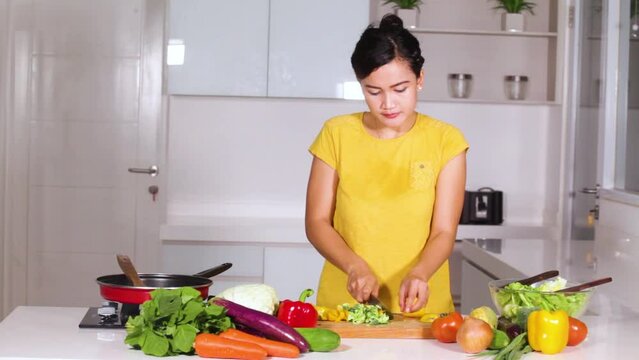 Young woman cut vegetables while preparing salad