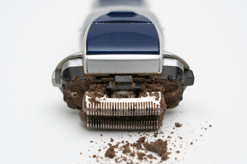 Disassembled electric shaver with remnants of hair close up on a white background