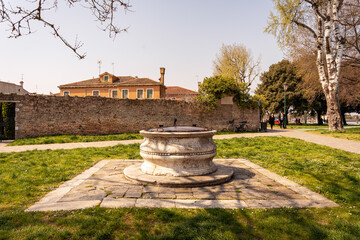 Burano old stone baroque well with a metal lid in the park, Venice, Venezia, Italy