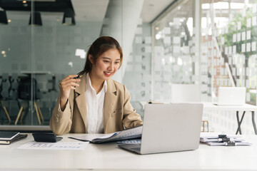 Young beautiful woman using her laptop while sitting in a chair at her working place.