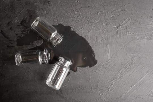 juego de tres frascos de vidrio con agua regada sobre madera negra con textura, monocrom&aacute;tico