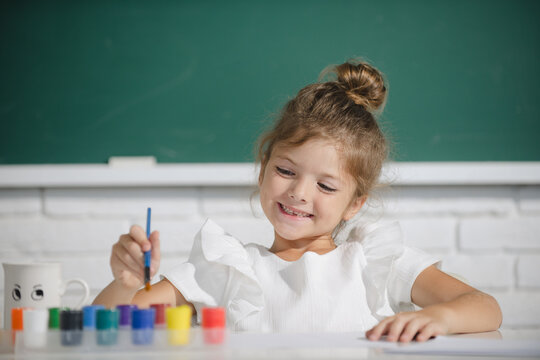 Painting school lesson, drawing art. Cute little preschooler child girl drawing at school. Child girl painting on elementary school.