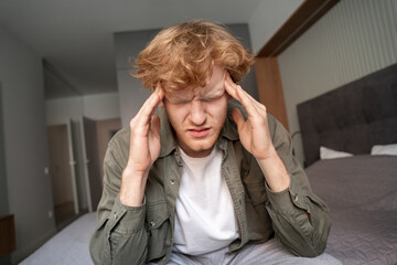 Young ginger man suffering from terrible headache or migraine closeup shot