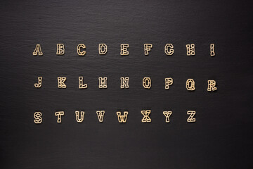 pasta letters or alphabet on a black slate background, diet and food concept, taken from above,...