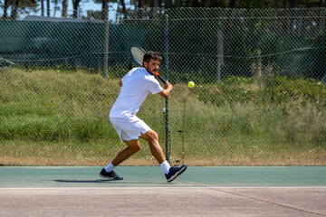 Tennis player hitting backhand at ball - obrazy, fototapety, plakaty