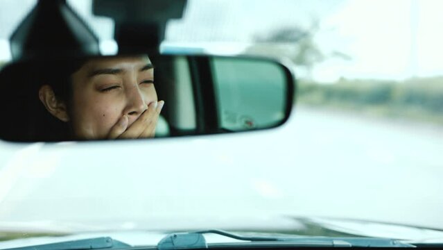 Rear view mirror. Young asian woman driver was drowsy. She yawned and was about to fall asleep. doze off Driving for a long time, sleep deprivation