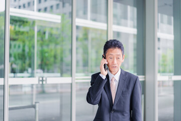 オフィス街で電話をするサラリーマンの男性