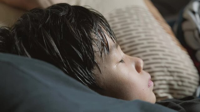 Sleeping tired Asian boy in mother arm with excessive sweating and hyperhidrosis symptoms over his face.