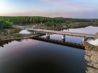 Obraz premium Beautiful view of the bridge across the Iset river in the city of Kamensk-Uralsky at sunset in spring. Kamensk-Uralskiy, Sverdlovsk region, Ural mountains, Russia.