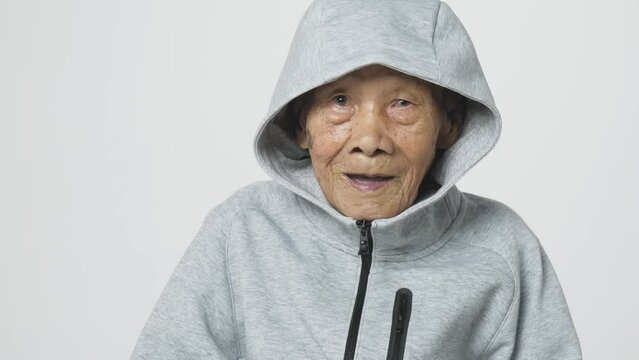 Senior Asian man wearing a hoodie sweater or cold weather zip sweatshirt. A 95 years old guy with a cataract eye problem with a gray cool shirt.