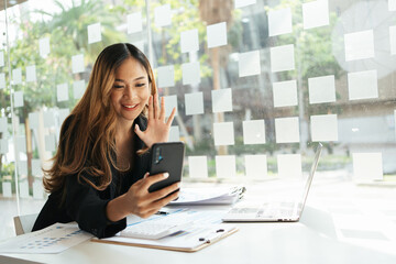 Happy businesswoman smiling and making video call via mobile phone at office.