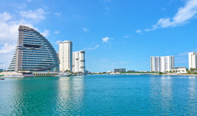 luxurious mexican marina in cancun large buildings in the background and boats on the tuquoise blue sea of cancun.