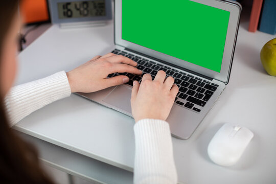 Green screen. At the desk, a girl quickly types a message on a laptop keyboard.