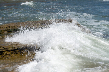 Splash wave rolls over ocean rocks
