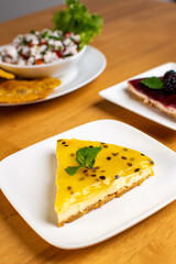 Beautiful passion fruit cheesecake with ceviche in a wood table and white plate