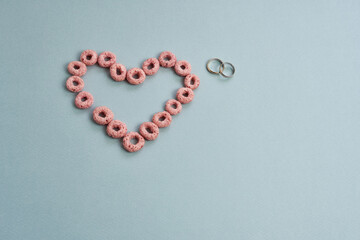 A heart and wedding rings on a colored background. The concept is marriage, love. Love Story.