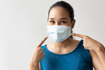 Happy woman wearing and pointing at face mask for seasonal flu and dust pollution protection
