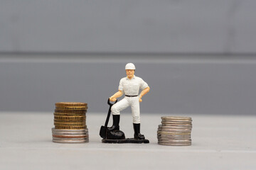 A toy of a farmer or worker with a shovel in his hands, next to the money. Symbol of work and...