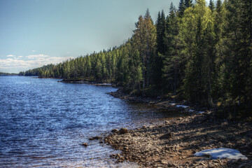 Rocky lakeside in Swedish Lapland with some snow and ice remnants in spring