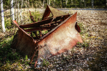 Historic rusty snow plow lying in the forest